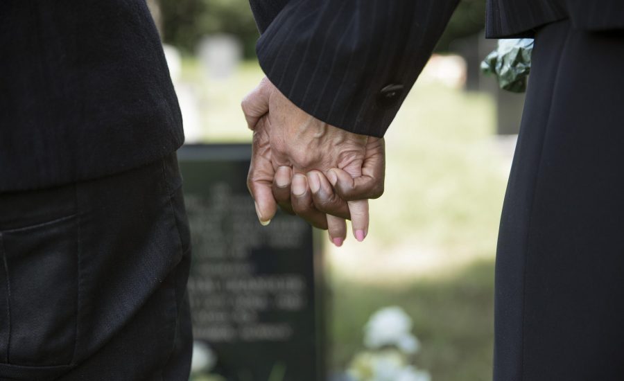close-up-people-holding-hands-by-the-grave-of-loved-one