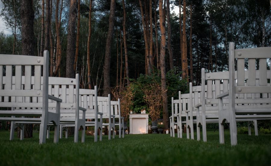 Look from  below at white benches standing before place for wedding altar in the garden